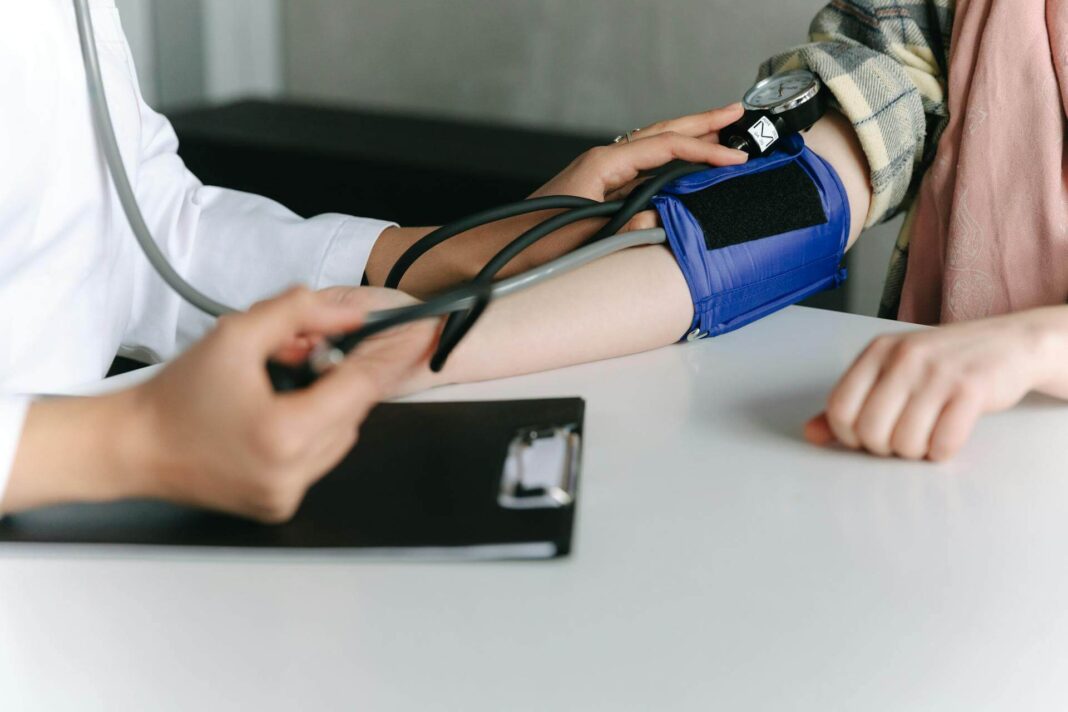 Kuo pavojingas žemas kraujo spaudimas – gydytojas matuoja paciento kraujo spaudimą sphygmomanometru.