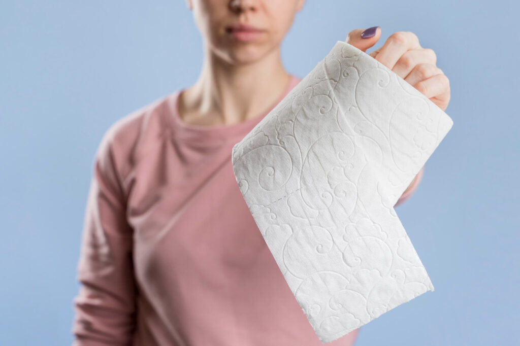 Kraujas išmatose gali sukelti susirūpinimą – moteris laiko tualetinį popierių, simbolizuodama galimą virškinimo sutrikimą.