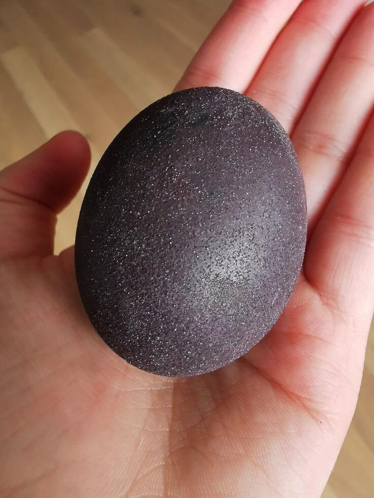 Margučių dažymas vynu – žėrintis juodas margutis laikomas rankoje