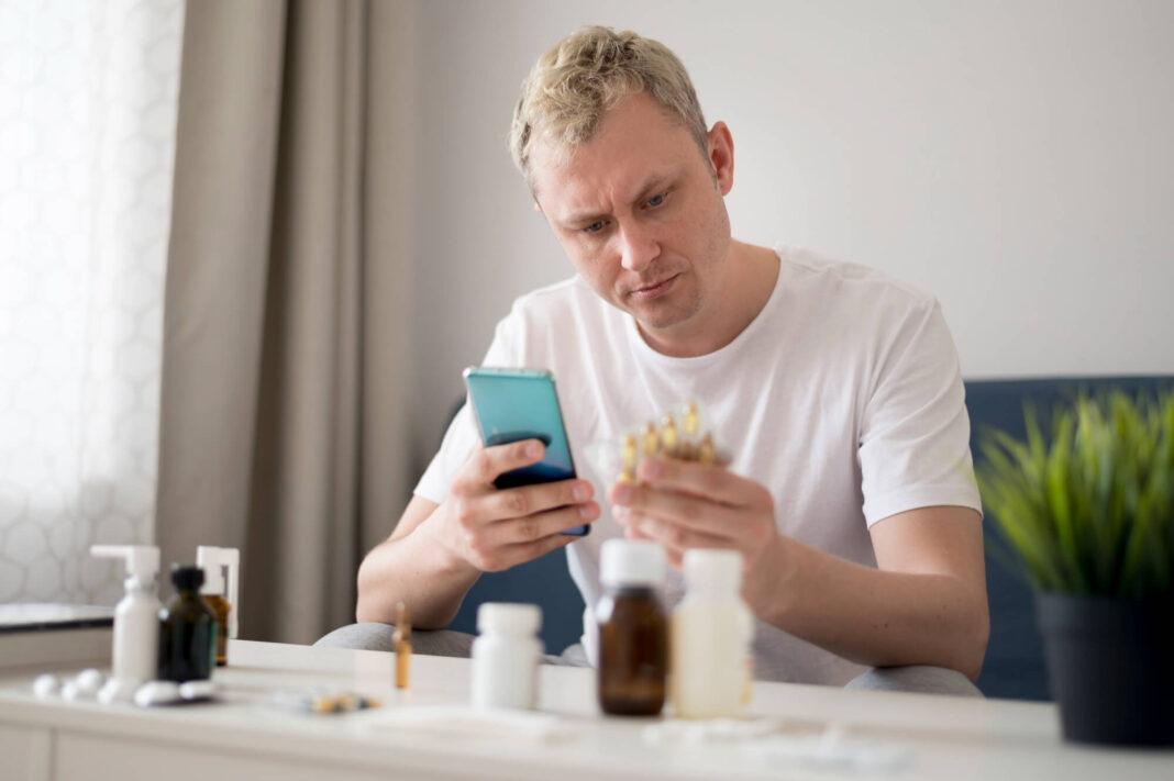 Vyras tikrina papildų poveikį ir ieško informacijos, kaip sumažinamas cholesterolio kiekis kraujyje.