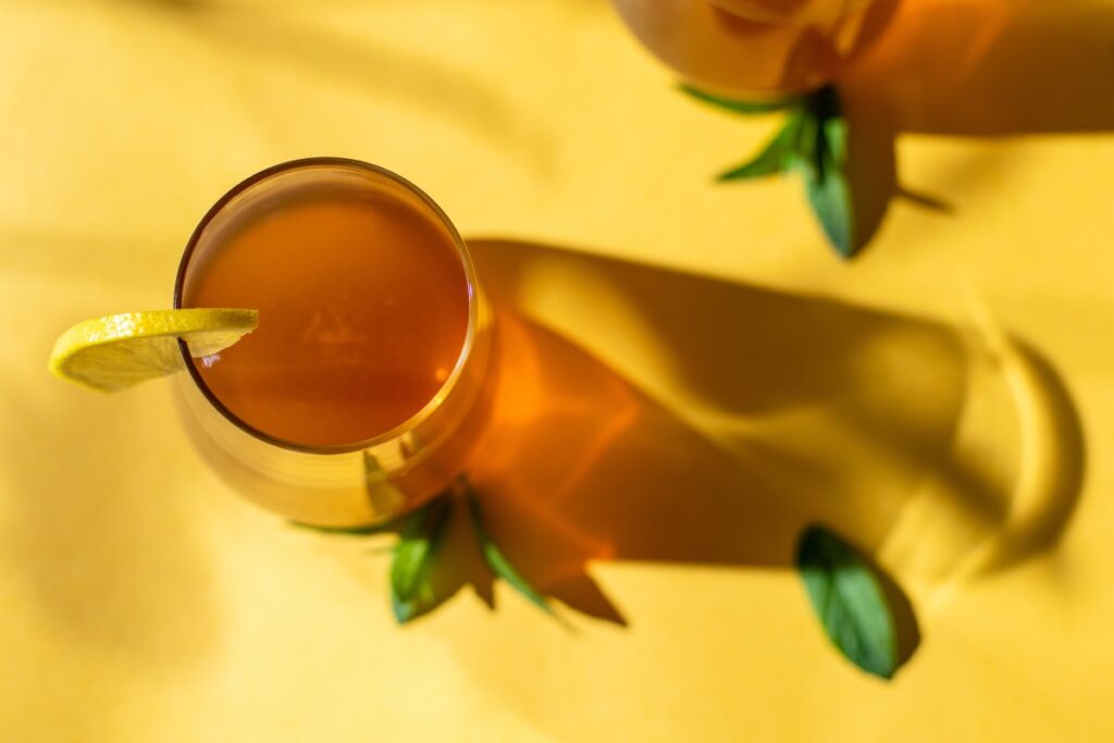 Gėrimas virškinimui gerinti su citrina ir mėtos lapeliais ant geltono fono