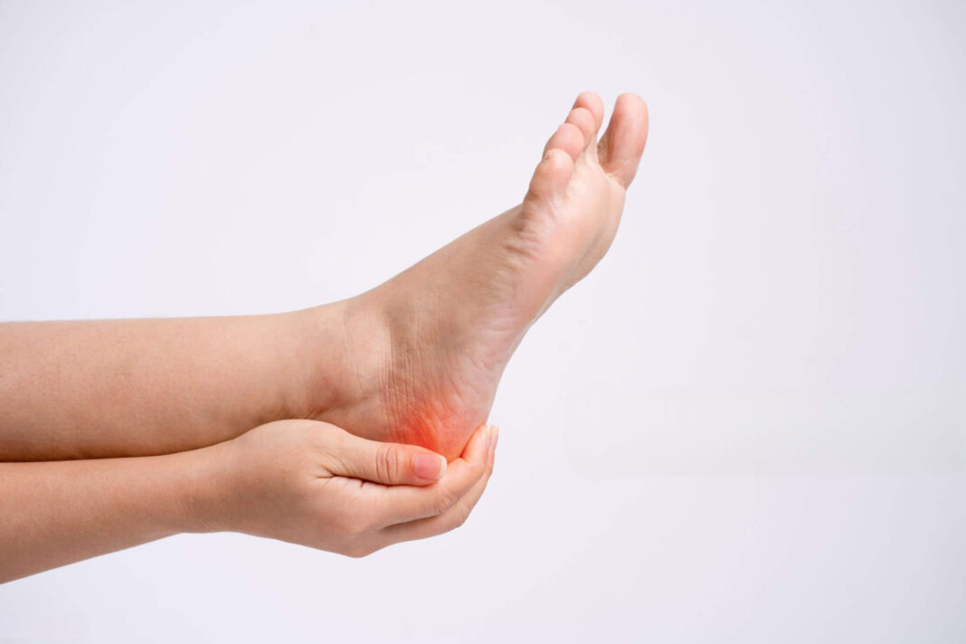 Kulno skausmas nuo kulno pentino – pėda laikoma rankomis, paraudęs plotas.