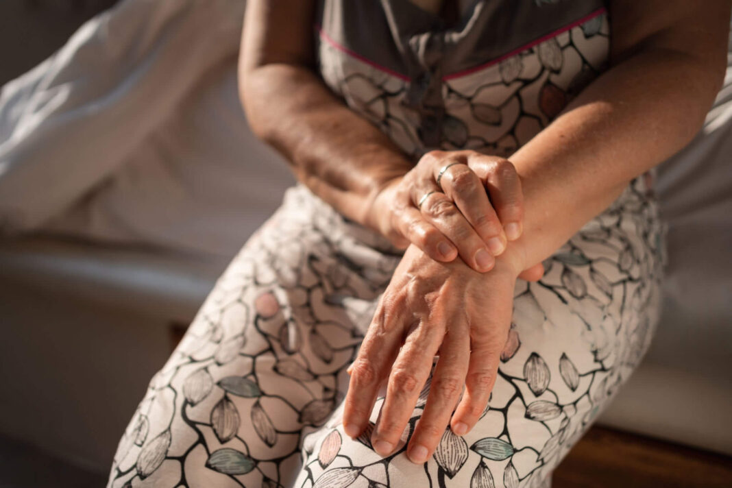 Vaistažolės nuo podagros – moteris laiko skaudančią ranką, sąnarių uždegimas.