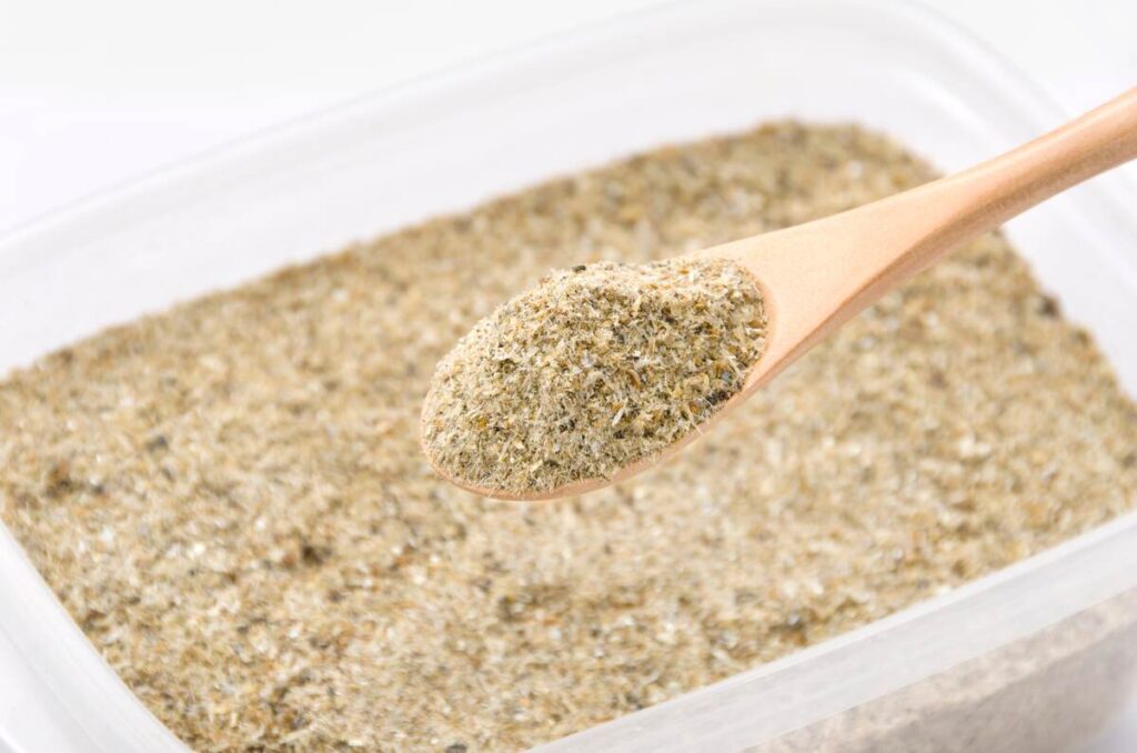 Žuvies miltai suberti į šaukštą – natūrali organinė trąša daržams