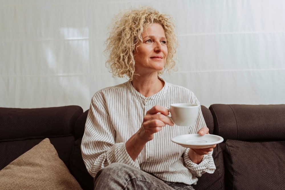 Kraujospūdį keliantis įprotis – moteris ramiai geria rytinę kavą, kuri gali turėti įtakos kraujospūdžiui visai dienai.