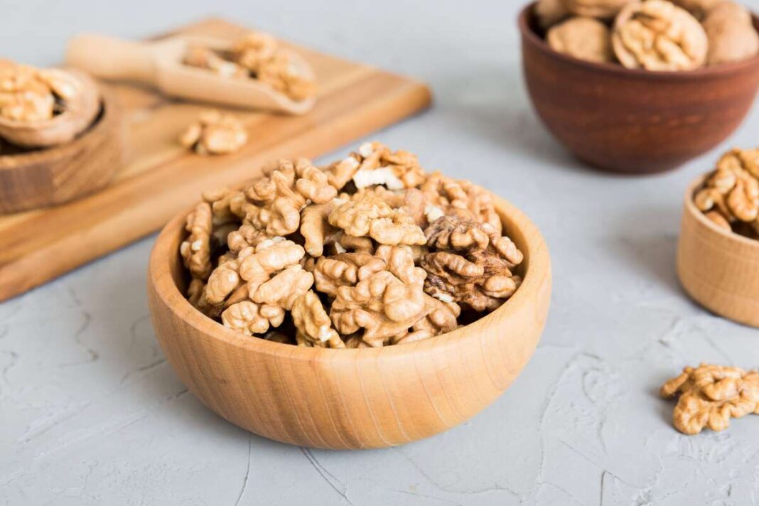 Gydymui graikiniais riešutais naudojami natūralūs riešutų branduoliai – medinėje dubenėlyje paruoštas maistingas sveikatinantis produktas.