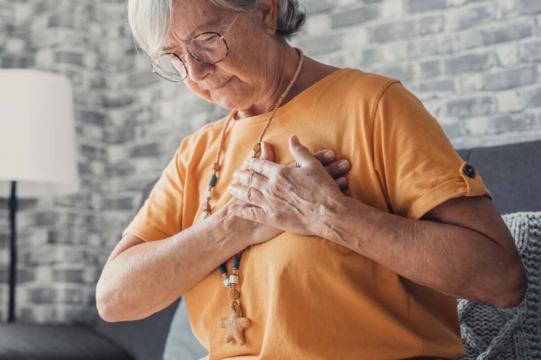 Vyresnio amžiaus moteris rankomis prilaiko krūtinę dėl širdies permušimų – pelkinė trindažolė gali padėti slopinti simptomus.