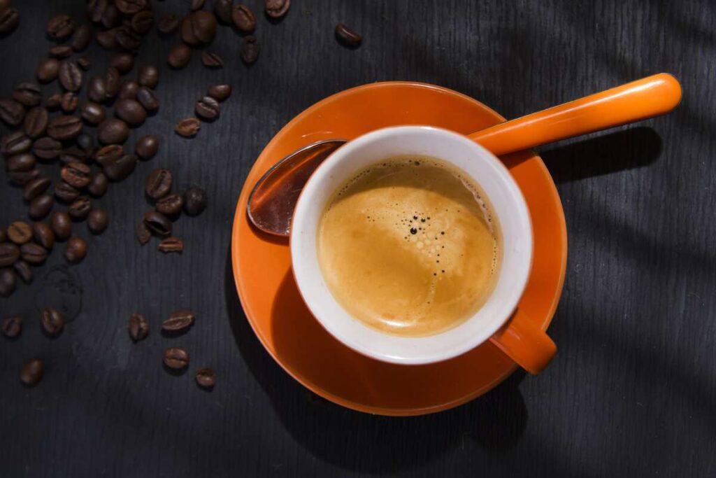 Juoda kava ilgaamžiškumui oranžiniame puodelyje – tyrimais patvirtinta nauda sveikatai ir gyvenimo kokybei.