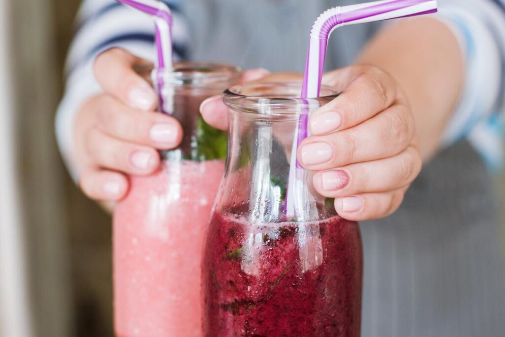 natūralios sultys širdies sveikatai – dvi stiklinės šviežiai spaustų burokėlių ir vaisių sulčių su šiaudeliais.