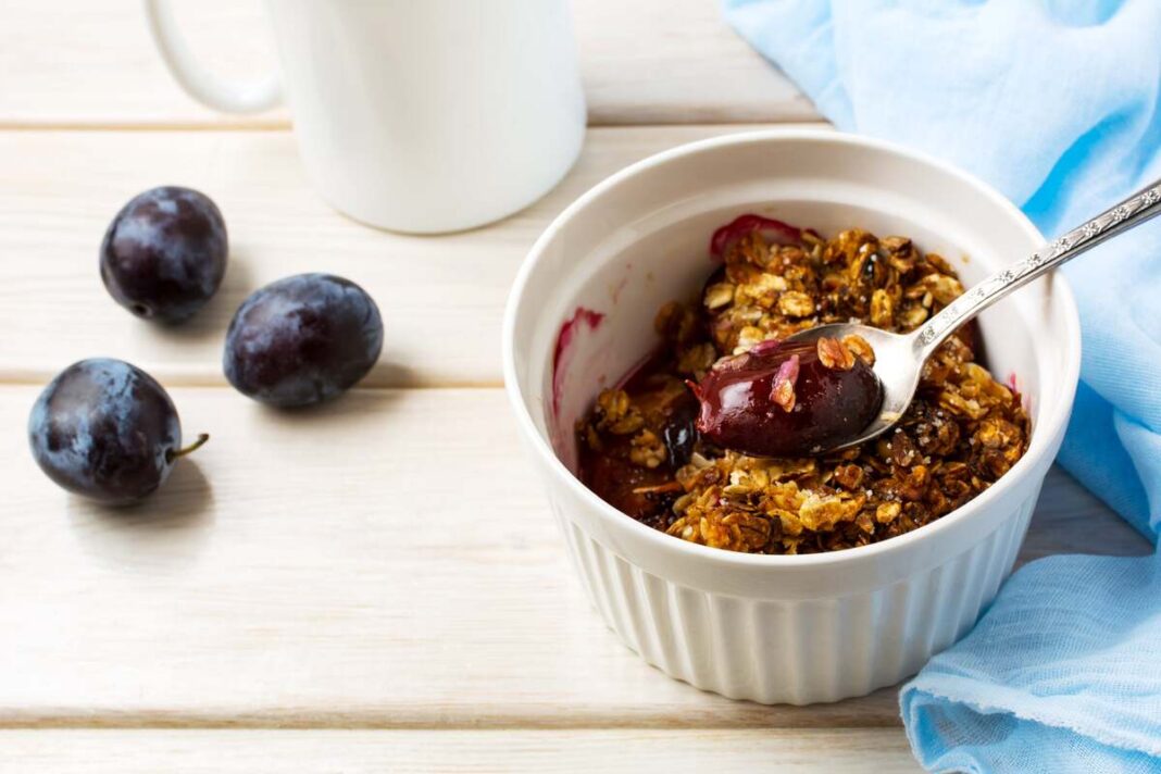 Pusryčių mišinys pilvui su avižiniais dribsniais ir slyvomis baltame inde – sveikas ir sotus pasirinkimas rytui.