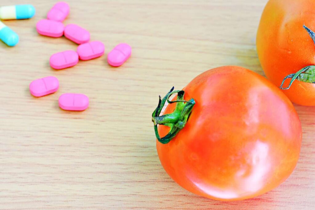 aspirinas pomidorams tabletės šalia prinokusio pomidoro ant medinio stalo