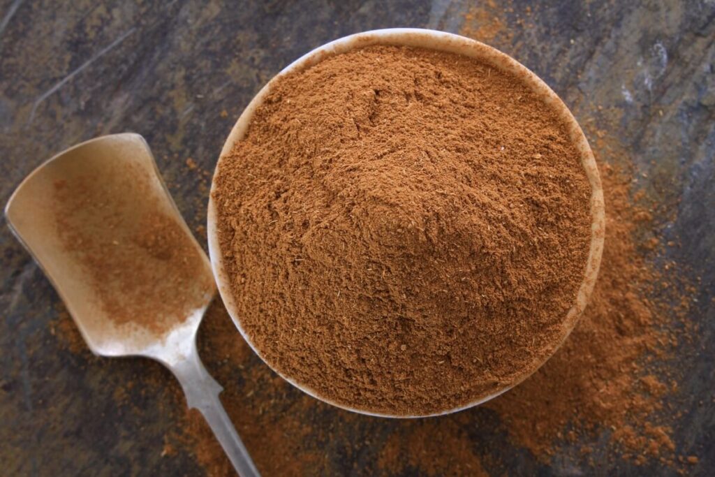 cinamono naudojimas sode su malto cinamono dubenėliu ant tamsaus paviršiaus