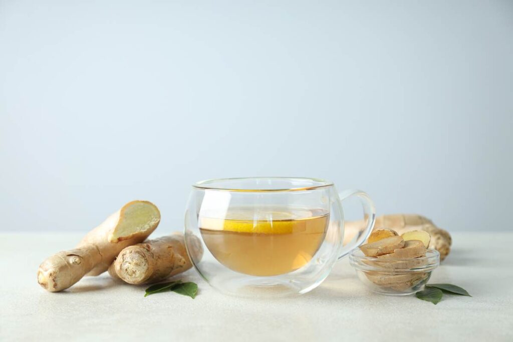 gerimas kūno detoksikacijai su imbieru ir citrina stikliniame puodelyje ant šviesaus stalo