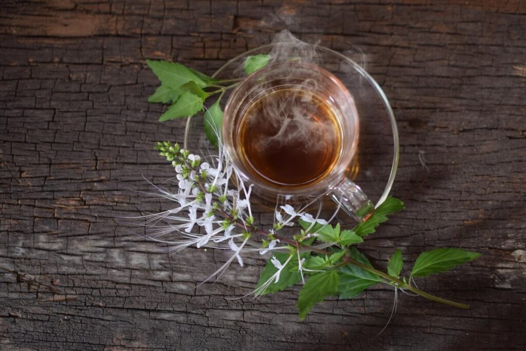 kas patinka inkstams – žolelių arbata puodelyje ant medinio stalo, palaikanti inkstų veiklą ir šalinanti toksinus.