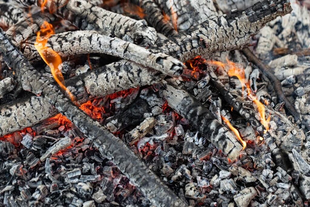 medžio pelenų nauda matomi degantys rąstai ir žarijos, susidarančios formuojantis natūraliems pelenams