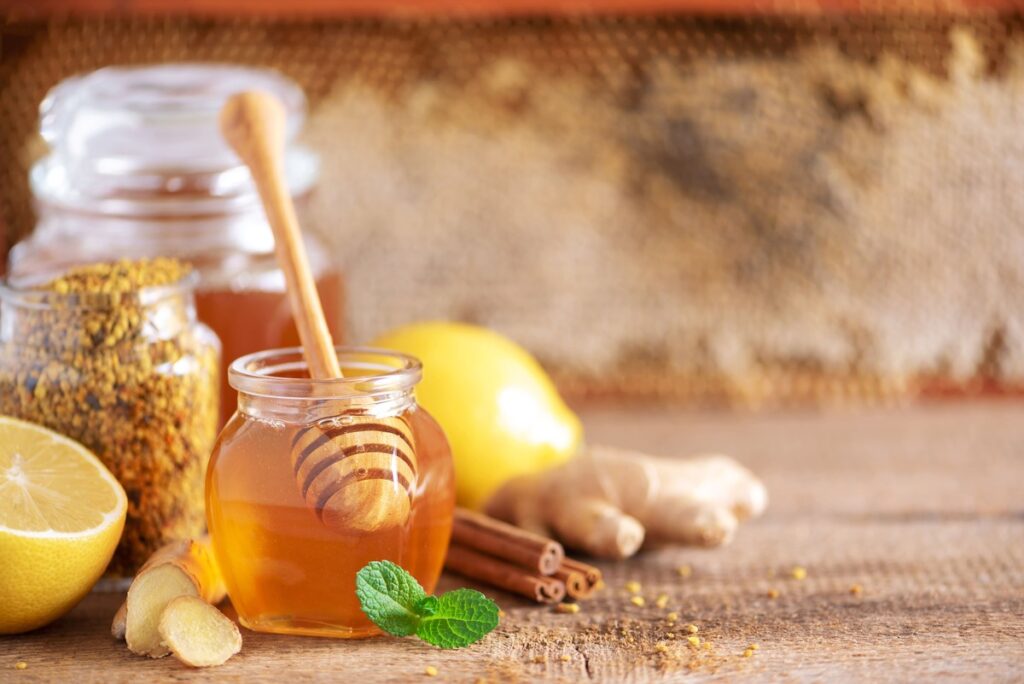 natūralus mišinys cholesterolio mažinimui – stiklainis su medumi, imbieru ir citrina ant medinio stalo.