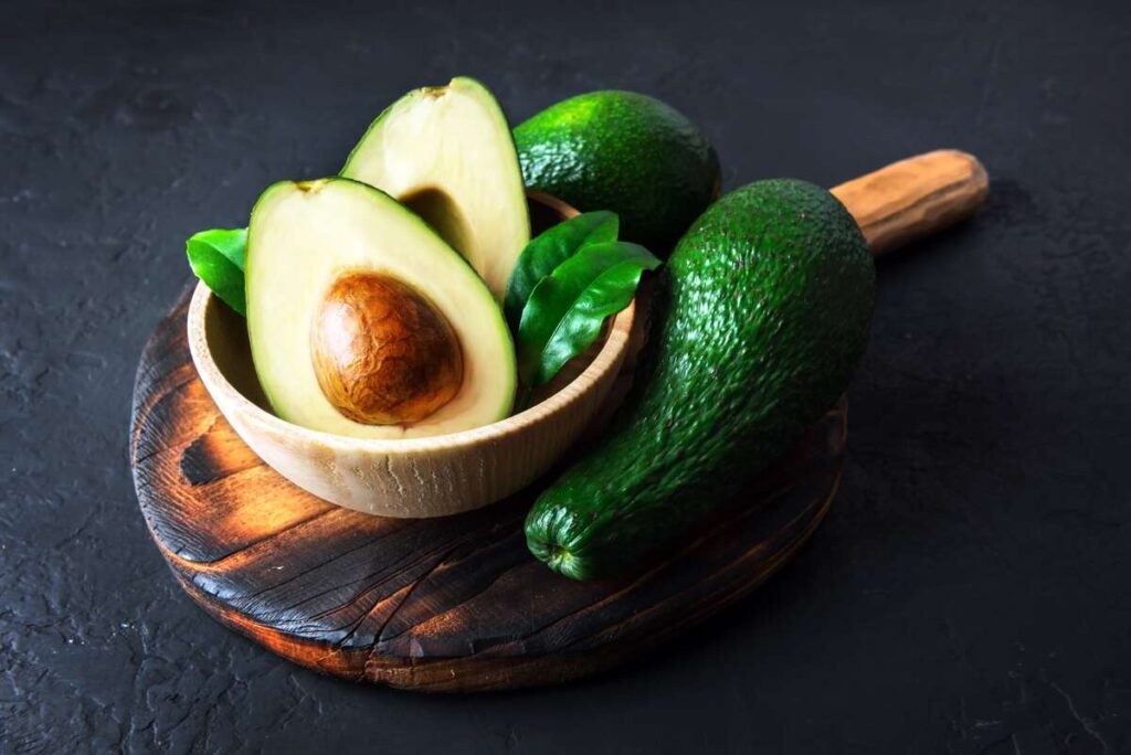 Neteisingas avokado valgymas – prinokęs avokadas perpjautas pusiau ir padėtas ant medinės lentelės.