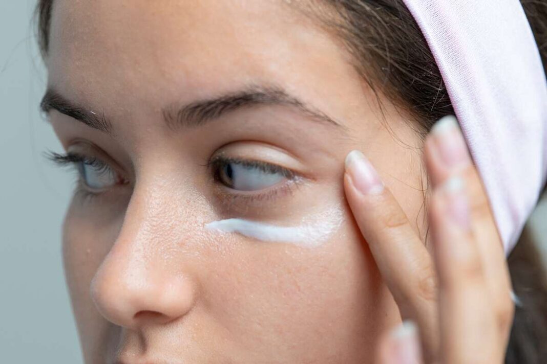 Pajuodusių paakių gydymas – moteris švelniai tepa paakių kremą, siekdama sumažinti tamsius ratilus ir atgaivinti odą.