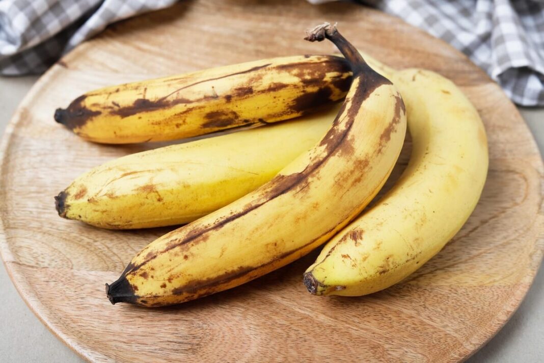 pernokęs-bananas-sode padėti ant medinės lėkštės – natūraliai sunokę vaisiai su tamsiomis dėmėmis