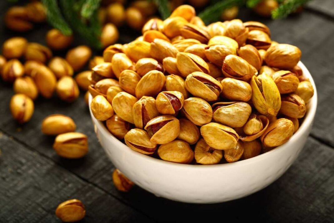 pistacijos prieš miegą dubenėlyje ant tamsaus stalo, vakaro užkandis