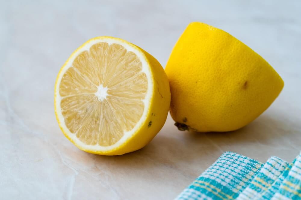Citrinos nauda organizmui – perpjauta citrina ir jos puselė ant virtuvės paviršiaus, paruošta vartojimui.