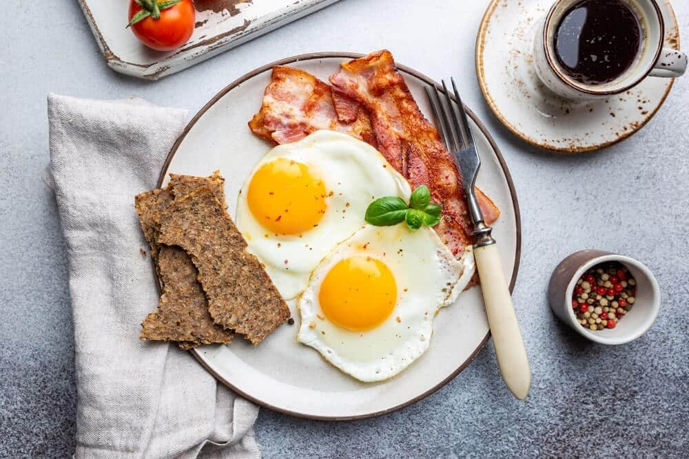 Kasdien tie patys pusryčiai – lėkštė su keptais kiaušiniais, duona ir kava kaip pastovus ryto pasirinkimas.