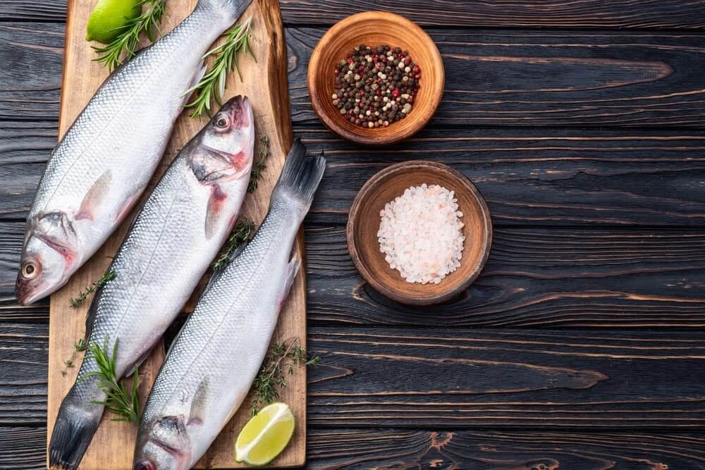 kiek kartų per savaitę valgyti žuvį vaizduoja ant lentos padėta šviežia visa žuvis su prieskoniais