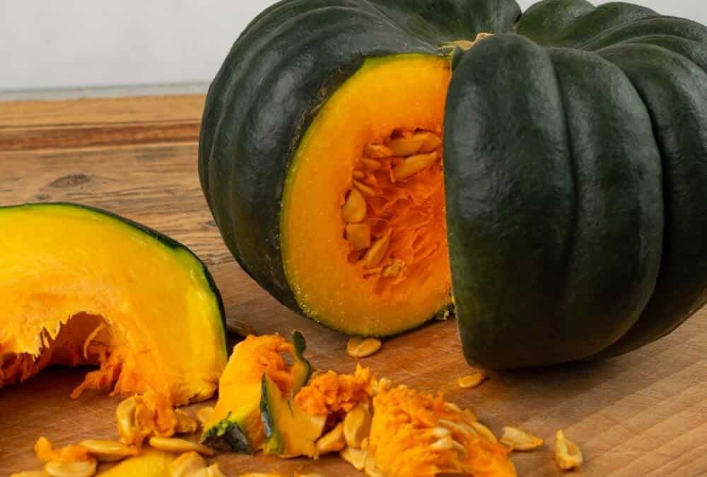 moliūgo nauda organizmui matoma perpjautame moliūge su sėklomis ant medinės lentos