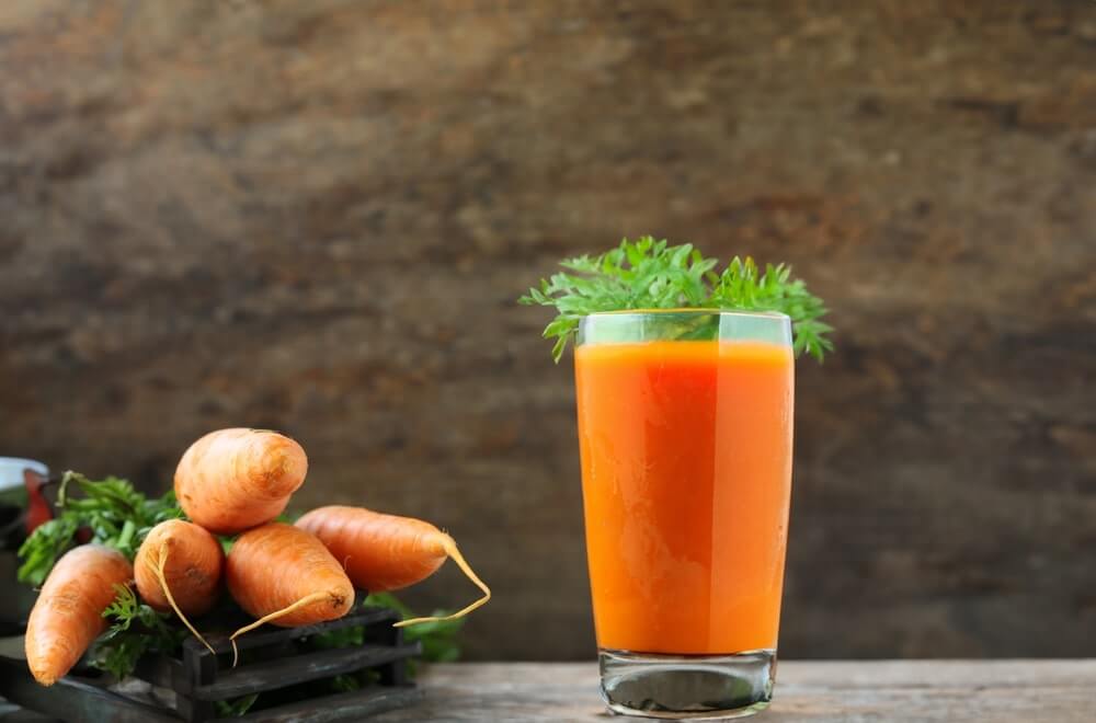 morkų sultys kasdien stiklinėje šalia šviežių morkų