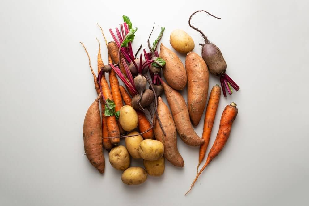 sveikiausi šakniavaisiai išdėlioti ant šviesaus fono su morkomis bulvėmis burokėliais ir saldžiosiomis bulvėmis