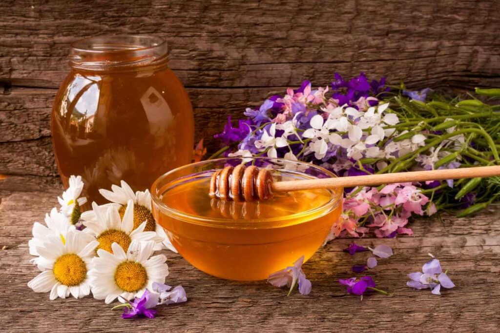 burnos opos natūralus gydymas medumi ir ramunėlėmis ant medinio paviršiaus