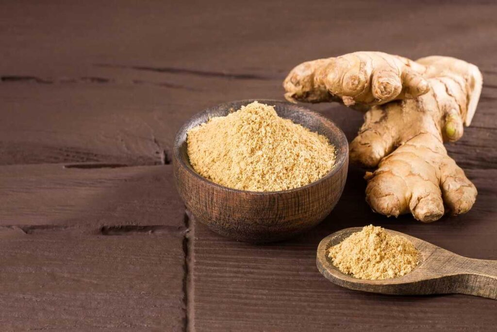 imbiero nauda imuninei sistemai maltas imbieras dubenėlyje ir šviežia imbiero šaknis ant medinio paviršiaus