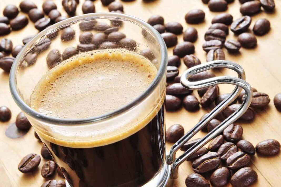 kava su kofeinu ar be jo juoda kava stikliniame puodelyje su kavos pupelėmis