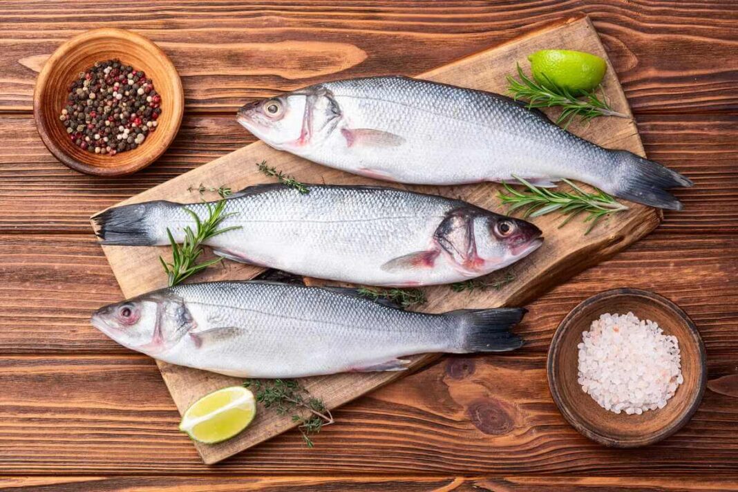 kurioje žuvyje daugiausia vitamino D švieži upėtakiai ant medinės lentos su prieskoniais