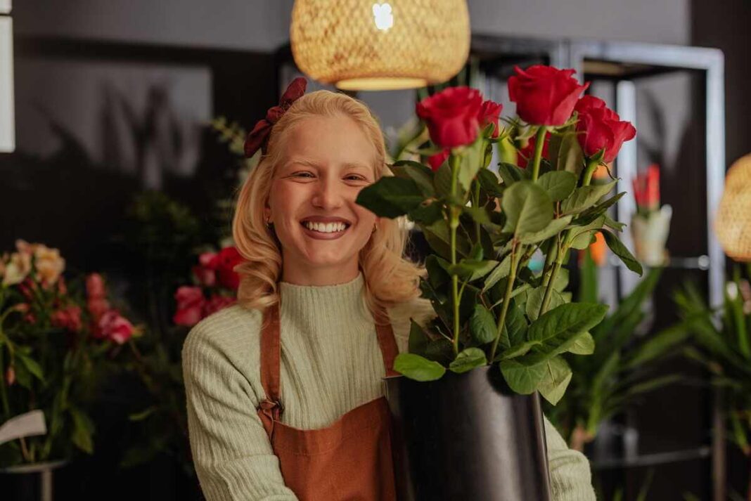 rožės greitai nuvysta, moteris floristė laiko šviežių rožių puokštę patalpoje