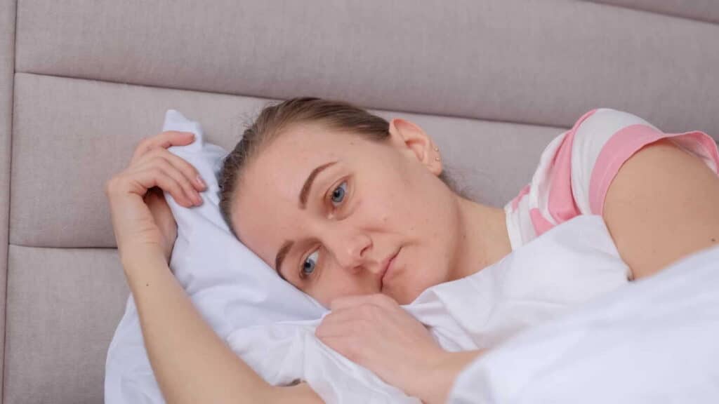 sutrikęs miego ritmas moteris guli lovoje ir atrodo pavargusi