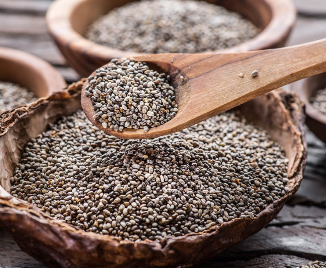 chia sėklos svoriui stambiame plane ant medinio šaukšto virš pilno dubenėlio.