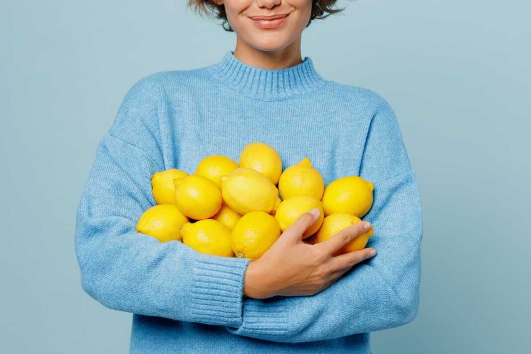 Citrinų laikymas yra aktualus, kai turimas gausus vaisių kiekis, kurį moteris mėlynu megztiniu laiko glėbyje