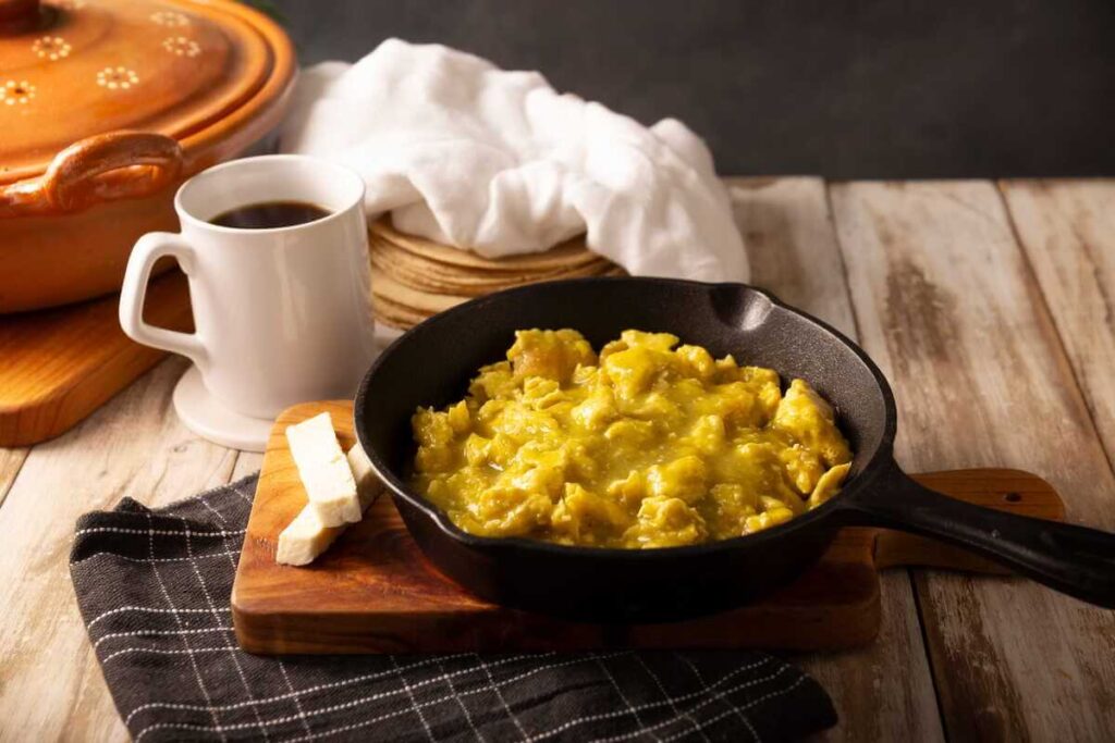 Kavos derinimas su maistu pateikiant puodelį juodo gėrimo šalia keptuvės su karštu kiaušinių patiekalu ir sūriu.