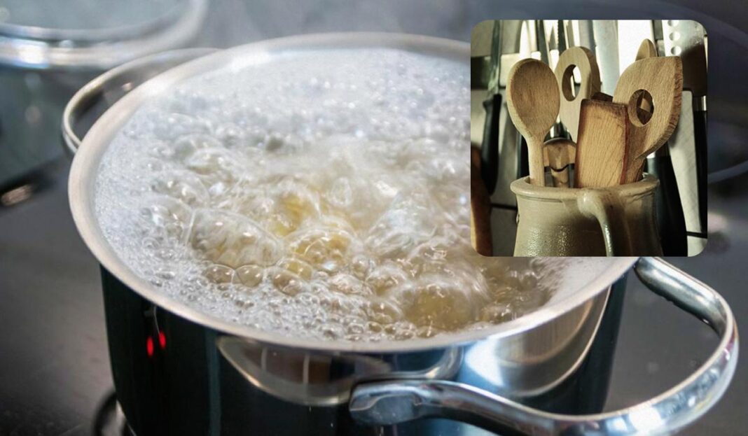 Verdantis puodas su kunkuliuojančiu vandeniu ir mediniais šaukštais įdėtinėje nuotraukoje