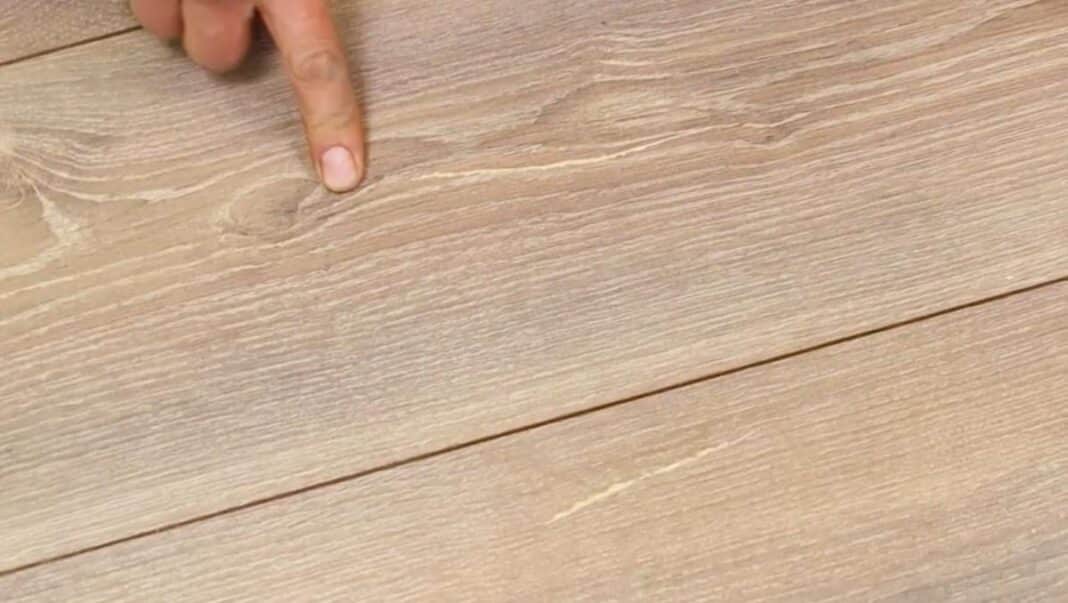 Pirštas rodo į įbrėžimą ant laminato paviršiaus